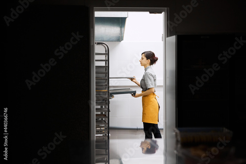 The pastry chef checks the readiness of the dish in the oven