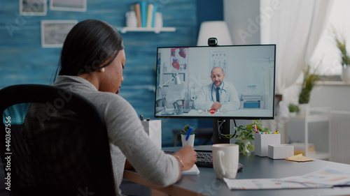 Fotografie African american woman writing respiratory sickness treatment on notebook discussing pills treatment during online healthcare videocall meeting conference