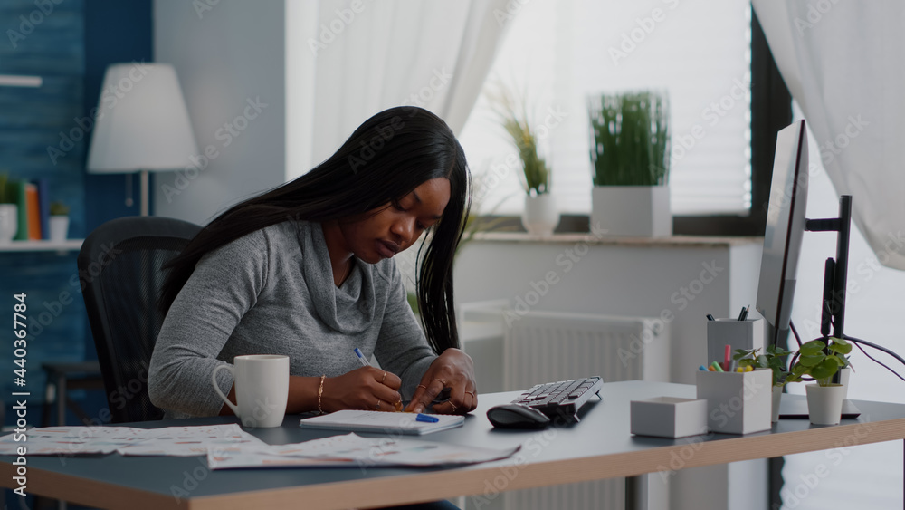 Black student writing education ideas on stickey notes sitting at desk table in living room. Young woman studying business at univeristy using elearning platoform working remote from home Black student writing education ideas on stickey notes sitting at desk table in living room. Young woman studying business at univeristy using elearning platoform working remote from home