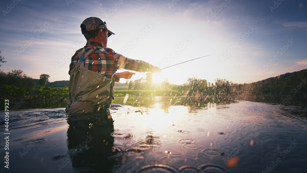 Fly fisherman stands in the water and casts the fly with fishing rod using Roll Cast with lot of splashes Fly fisherman stands in the water and casts the fly with fishing rod using Roll Cast with lot of splashes