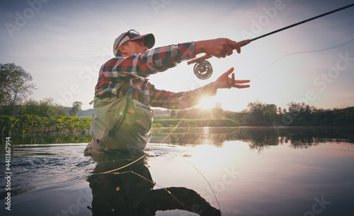 Foto Fly fisherman stands in the water and casts the fly with fishing rod using Roll