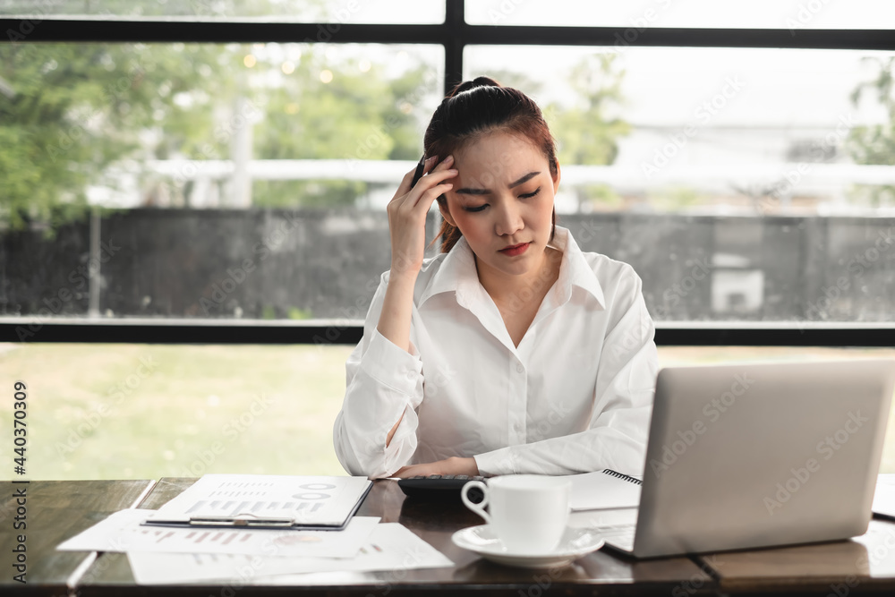 Asian businesswoman holding a pencil sit and think a lot stressed over the papers on the desk with laptop at the office. Asian businesswoman holding a pencil sit and think a lot stressed over the papers on the desk with laptop at the office.