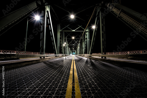 Night time photo from the center of the Hawthorne Bridge in Portland, Oregon. A straight, empty dimly path in front. photo