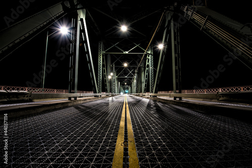 Night time photo from the center of the Hawthorne Bridge in Portland, Oregon. A straight, empty dimly path in front.