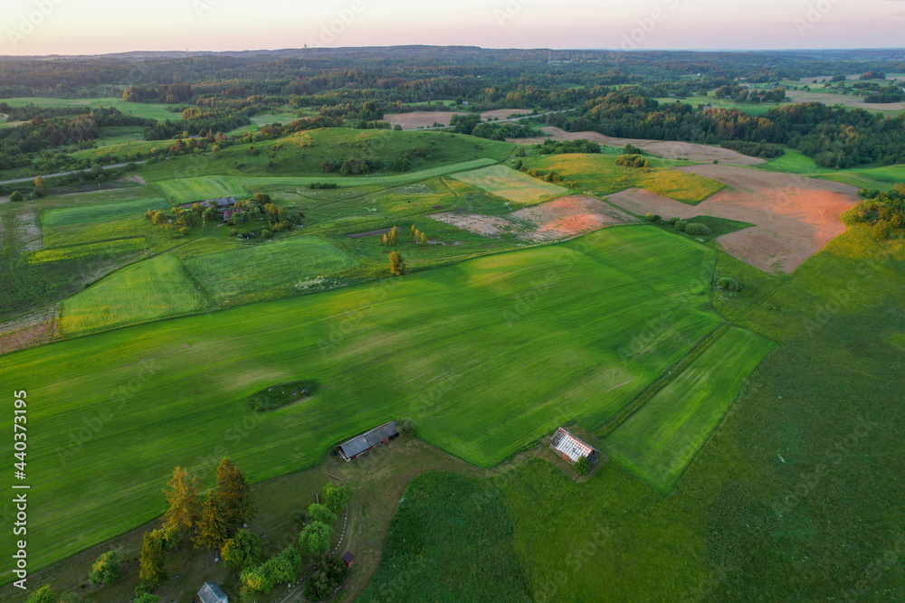 A beautiful view of forests and green fields from above with a sun on golden hour. Drone photography of Europe agricultural region.