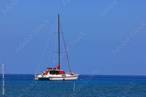 ハワイ島（ビッグアイランド）、青い海、青い空、白い雲。帆を降ろしたヨットが一艘。