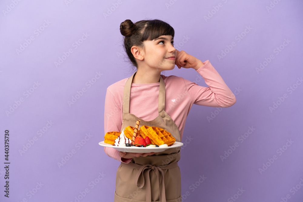 Little caucasian girl holding waffles isolated on purple background having doubts and thinking Little caucasian girl holding waffles isolated on purple background having doubts and thinking