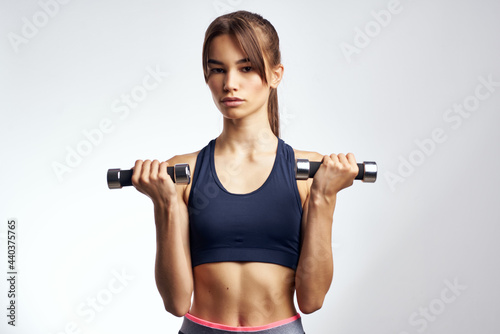 pretty athletic woman with dumbbells in hands pumping up muscles fitness