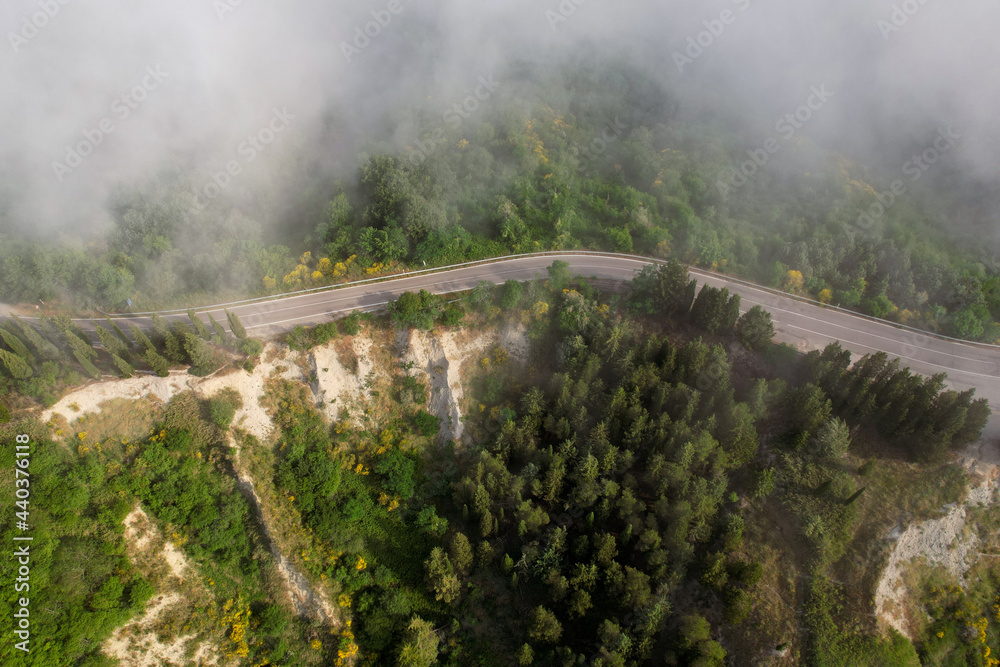 Karst landscape in Tuscany near Chiusure photographed with a drone. Fields, valley of Toscana, Siena region in Italy with little road and morning fog, mist. Small village of Chiusure.