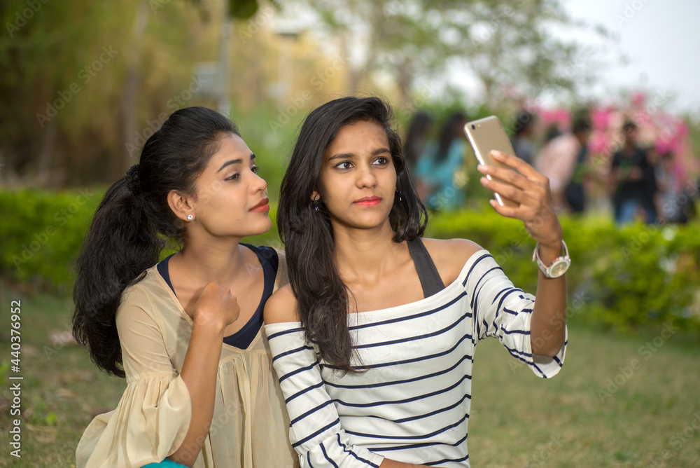 Two beautiful female friends taking selfie with smartphone in outdoors. Two beautiful female friends taking selfie with smartphone in outdoors.