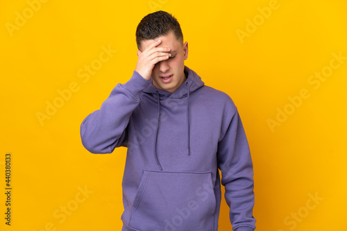 Young caucasian man isolated on yellow background with headache