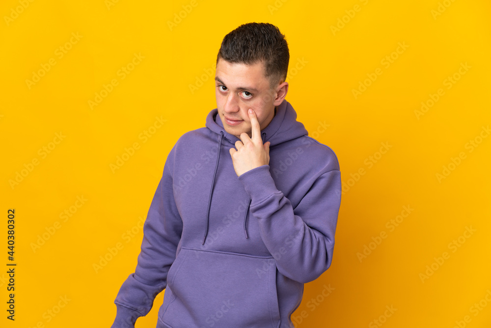 Young caucasian man isolated on yellow background showing something Young caucasian man isolated on yellow background showing something