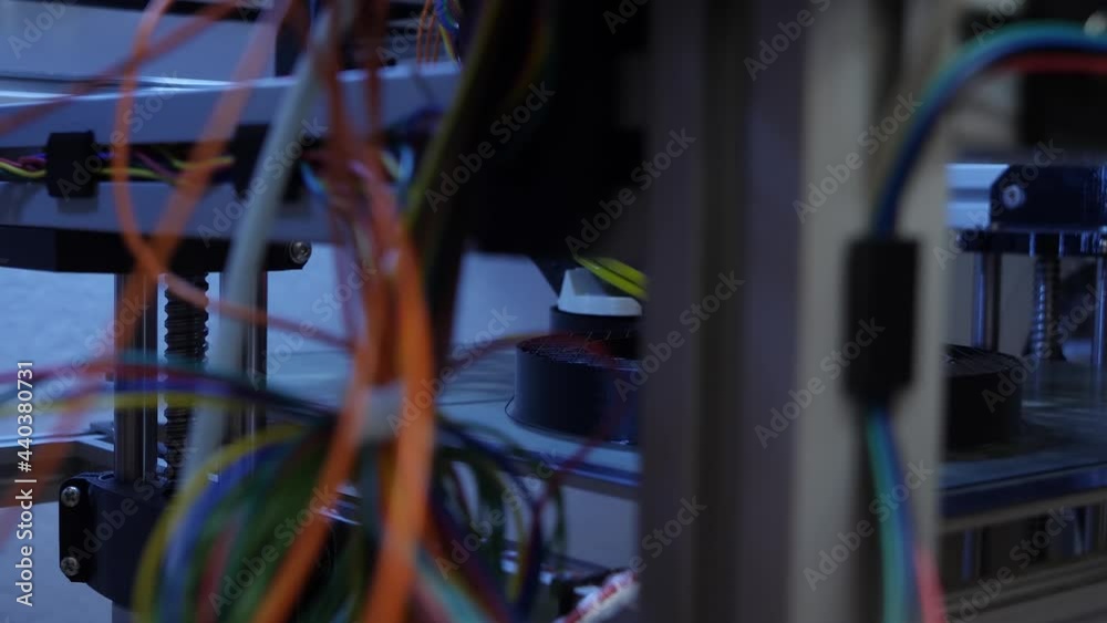 Dolly right shot reveals 3D printer printing out a new black plastic prototype.