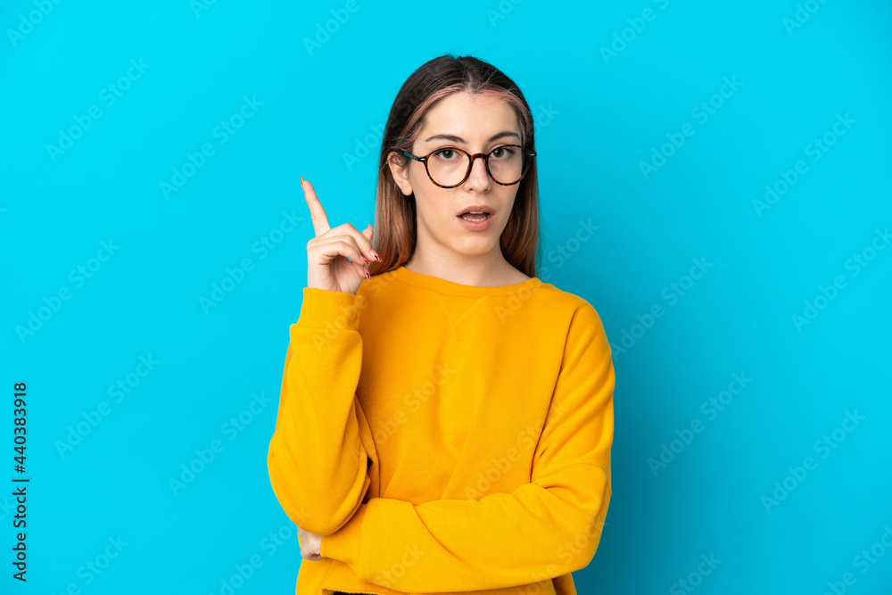 Young caucasian woman isolated on blue background thinking an idea pointing the finger up Young caucasian woman isolated on blue background thinking an idea pointing the finger up