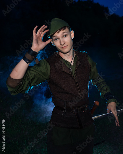 Cosplay on Peter Pan. A young man in a Peter Pan costume stands amid blue smoke at night