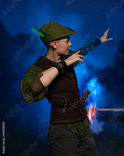 Cosplay on Peter Pan. A young man in a Peter Pan costume stands amid blue smoke at night