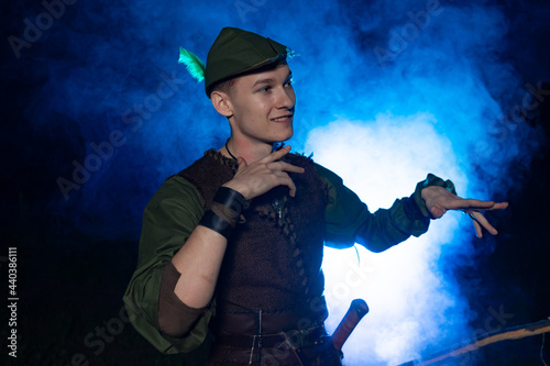 Cosplay on Peter Pan. A young man in a Peter Pan costume stands amid blue smoke at night