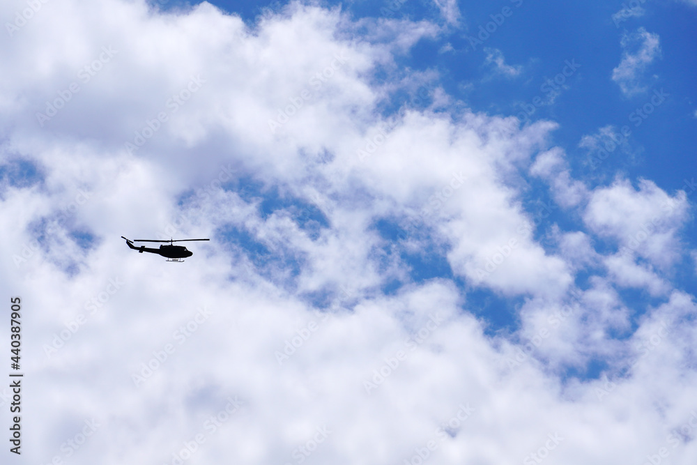 青空に爆音を轟かせながら飛ぶヘリコプター