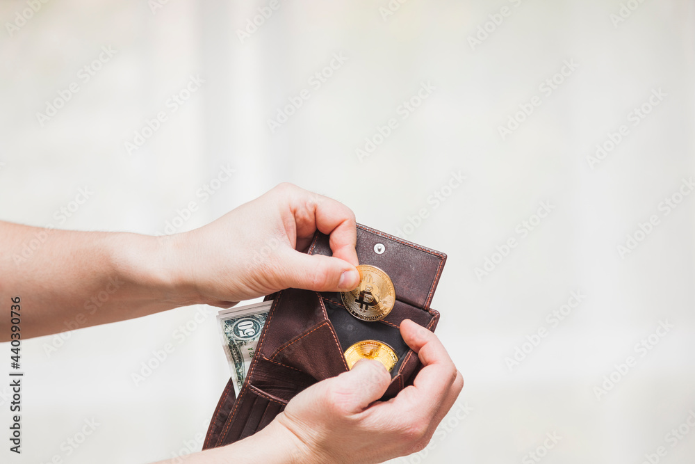 Fototapeta premium Hands removing bitcoins from a wallet
