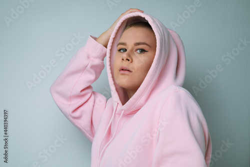 Caucasian woman posing on white background, pulling the hood over the heads.