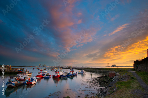 Small Fishing Boats in a Small Harbour with the Commercial Docks and a Dramatic Sunset photo
