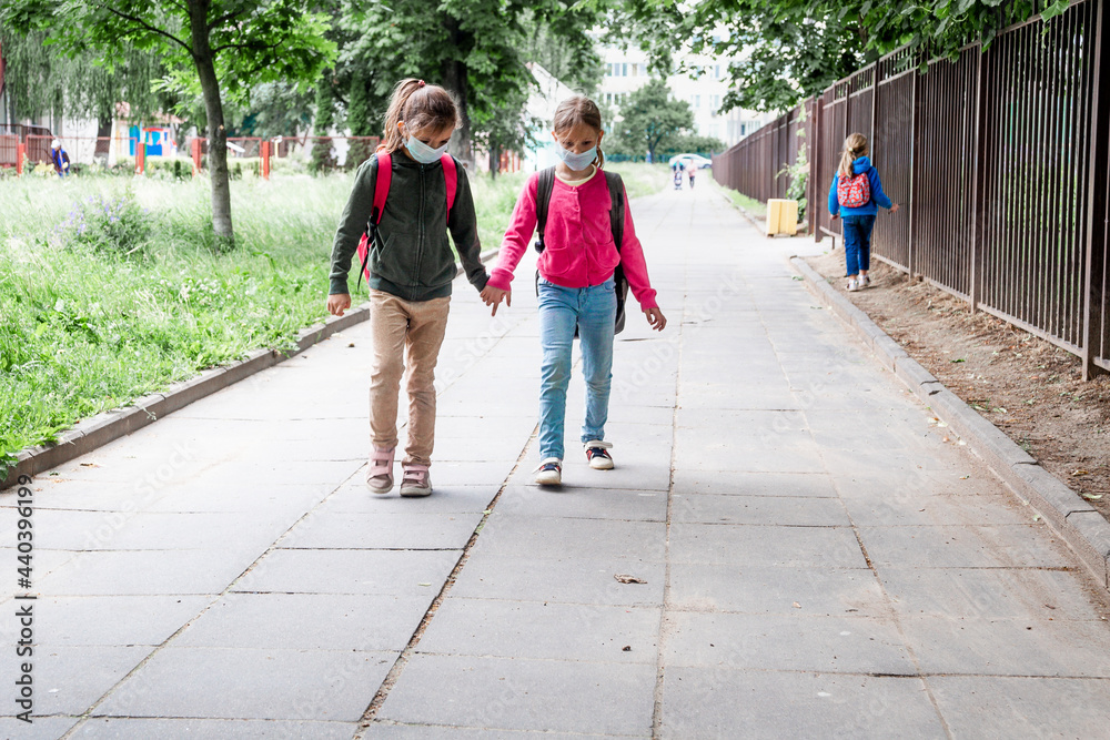 Two girls wearing protective face mask and going back to school during coronavirus pandemic.