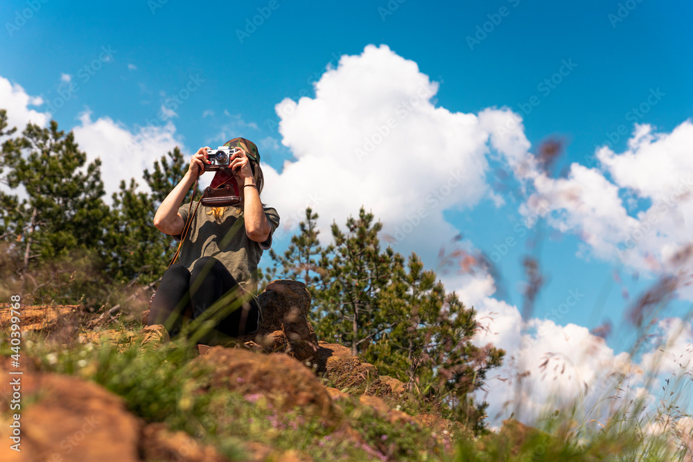 Tourist girl photographing with vintage photo camera at the top of the mountain peak