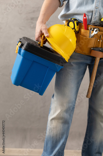 Man worker holding construction helmet and toolbox near wall. Male hand and construction tools