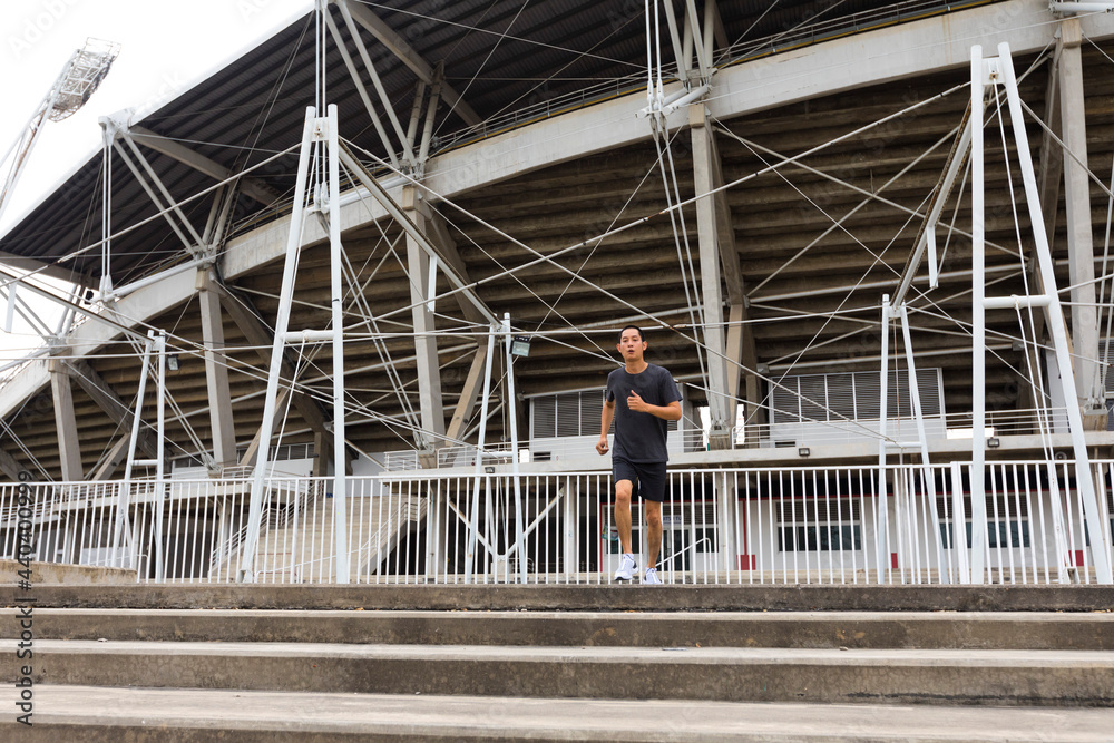Young athlete asian man running in front of the stadium. The man trains outdoors. Preparing for the marathon. Young athlete asian man running in front of the stadium. The man trains outdoors. Preparing for the marathon.