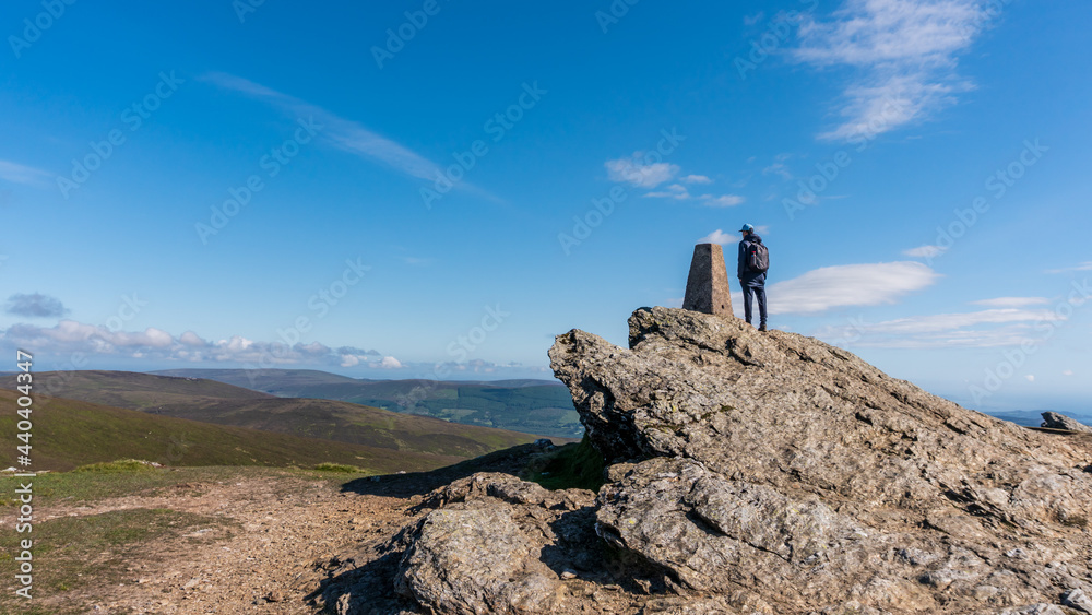 Hiker on top of the Djouce Mountain in Wicklow, Ireland, enjoying the view.