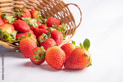Strawberries  beautiful strawberries dropped from a straw braided basket onto a white surface  selective focus.