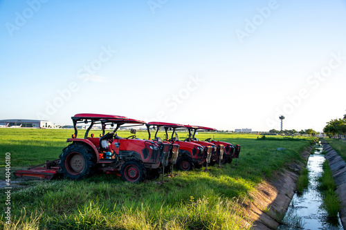 Red tractors parking in a grass field with blue sky background and small stream water. photo
