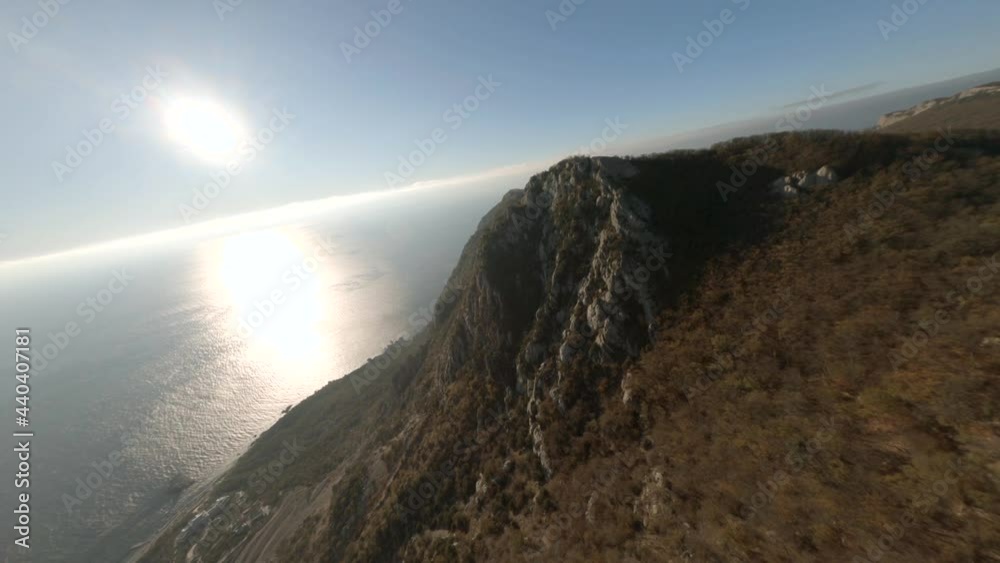 Hilly landscape with white rocky cliffs and green dense forests on coastline against sea with sunlight reflections. Aerial fpv sport drone view Hilly landscape with white rocky cliffs and green dense forests on coastline against sea with sunlight reflections. Aerial fpv sport drone view
