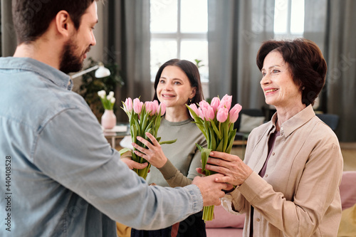 Cheerful females with tulips looking at kind young man