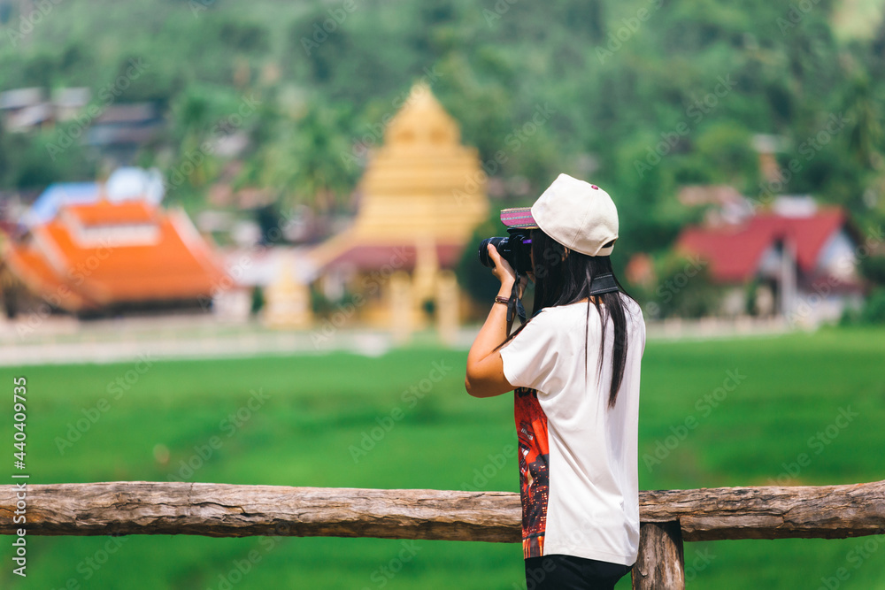 woman in a hat taking photos the old temple on a fence