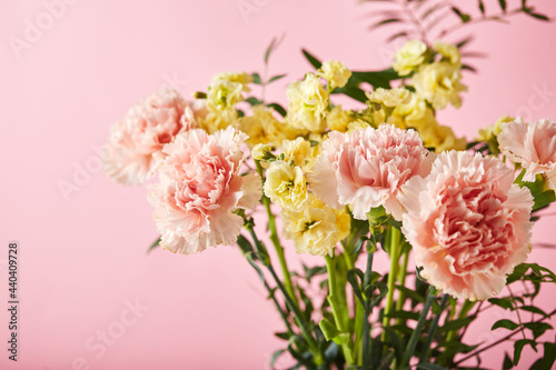 Bouquet of pink carnations and yellow matthiola with green branches. Design concept of holiday greeting with carnation bouquet on pink background