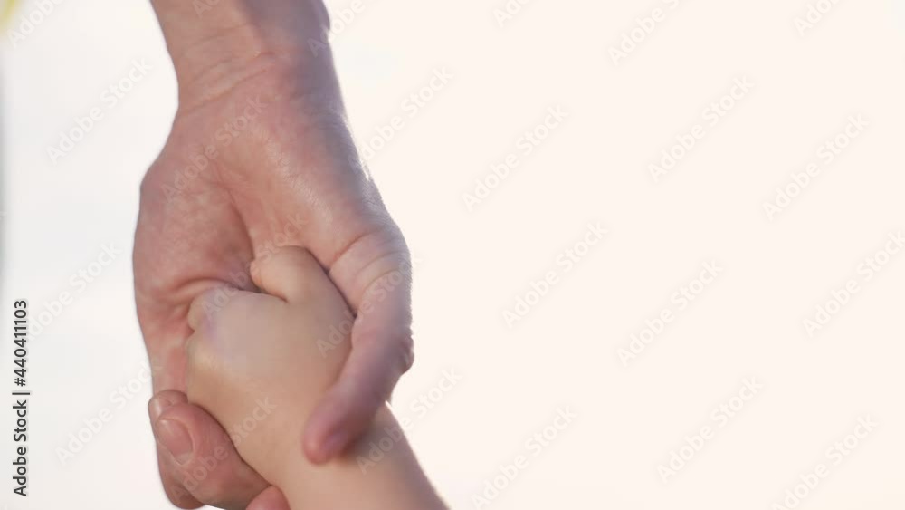 Helping hand. Mom holds baby by hand. Family teamwork. Happy kid holds mom hand. Family in park. Family team. Happy mom with baby. Happy kid. Family walk in park at sunset. Teamwork and helping hand Helping hand. Mom holds baby by hand. Family teamwork. Happy kid holds mom hand. Family in park. Family team. Happy mom with baby. Happy kid. Family walk in park at sunset. Teamwork and helping hand