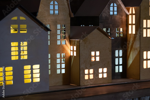 Toy houses made of plywood with burning windows. Evening city.