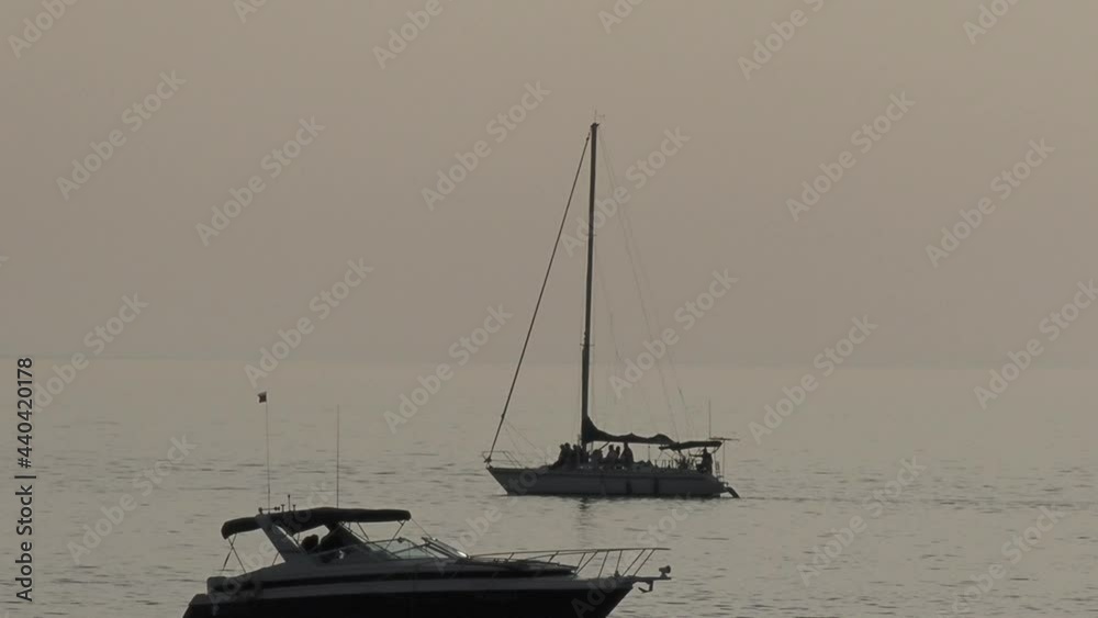 Silhouette of sailing yacht with passengers onboard. Sea cruise at sunset. People travel by sea on modern yacht. Silhouette of sailing yacht with passengers onboard. Sea cruise at sunset. People travel by sea on modern yacht.