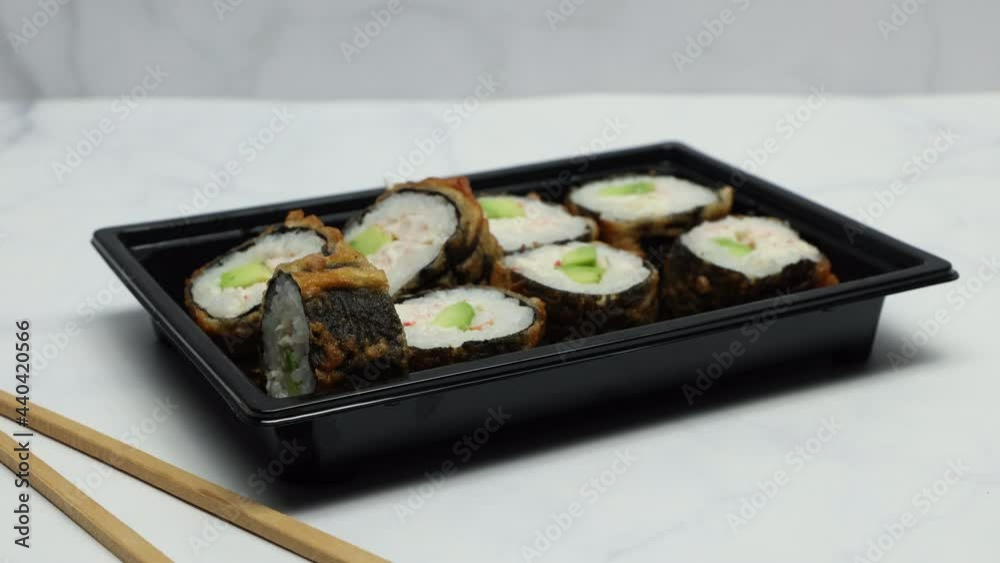 Sushi Rolls In Plastic Box With Chopsticks On Kitchen Marble Table Background. Panning Slider Shot. Sushi Rolls In Plastic Box With Chopsticks On Kitchen Marble Table Background. Panning Slider Shot.