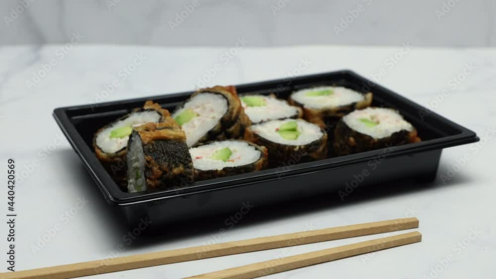 Sushi Rolls In Plastic Box With Chopsticks On Kitchen Marble Table Background. Slider Shot. Sushi Rolls In Plastic Box With Chopsticks On Kitchen Marble Table Background. Slider Shot.