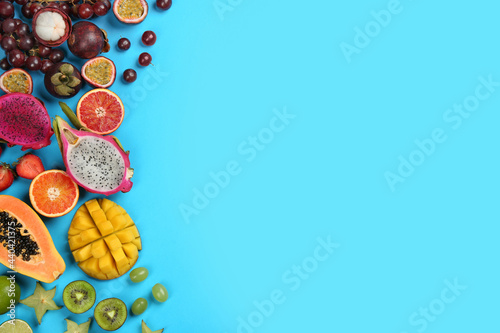 Many different delicious exotic fruits on light blue background, flat lay. Space for text