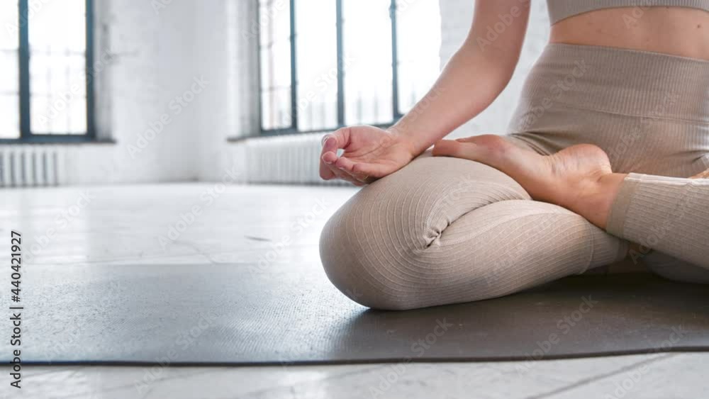 Sportive lady in leggings sits in yoga lotus pose on mat Sportive lady in leggings sits in yoga lotus pose on mat