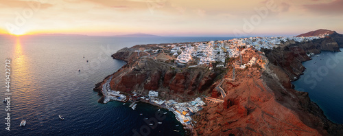 Panorama of Santorini island during sunset time with the village Oia on the edge of the caldera and the port of Ammoudi underneath, Cyclades islands, Greece