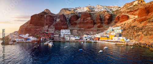 Panoramic view to the beautiful bay of Ammoudi with the restaurants and fishing boats in golden sunset light, Santorini, Greece photo