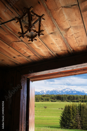 Fototapeta Naklejka Na Ścianę i Meble -  The Tatra mountain range visible through the entrance door to a wooden highlander cottage among fields and meadows.
