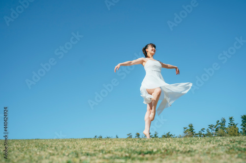空と白いワンピースの踊る女性（ピルエット）
