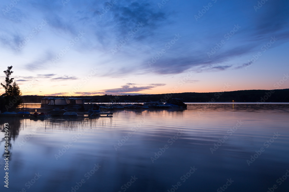 Pontoons and boats docked in Lovering Lake seen at sunrise during a blue hour morning, Magog, Quebec, Canada