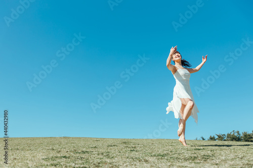 空と白いワンピースの踊る女性 