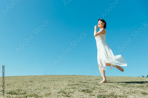 空と白いワンピースの走る女性 